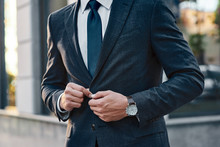 A Young Businessman Fastens A Suit Jacket. He Has On His Hands An Expensive Watch.