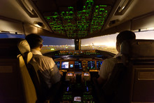 Inside Cockpit On Ground At An Airport, Both Pilots Are Operating The Airplane Moving To The Runway. Seen From Observer Behind Pilots Seat In The Night Time. Modern Aviation Concept.