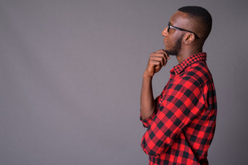 Young handsome African man with short hair against gray backgrou