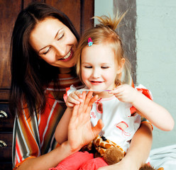 Wall Mural - Portrait of mother and daughter laying in bed and smiling close 