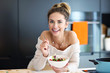 © Kalim - Beautiful Smiling Woman Eating Fresh Organic Vegetarian Salad In Modern Kitchen