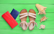 Leinwandbild Motiv Fashionable women's sandals, passport, red purse, seashells on green wooden floor. The concept of traveling to the sea. Top view..