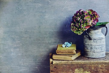 Hydrangea flowers in grunge zinc vase can on vintage wooden cabinet. Hygge home interior concept