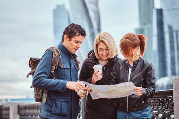 Wall Mural - Group of tourists searching place on the map in front of skyscrapers