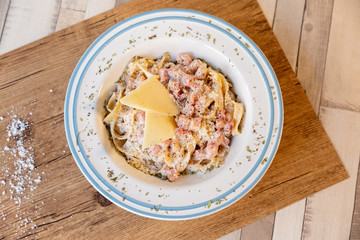 A top view of a carbonara spaghetti plate on a wooden table