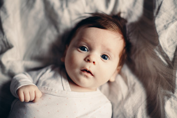 closeup portrait of cute adorable funny white caucasian brunette little baby newborn with blue grey 