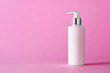 White bottle of moisturizing lotion on pink background with copy space. Minimalism style. Skin care, body treatment, beauty concept