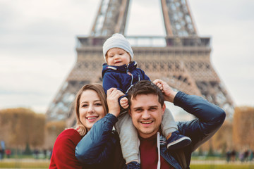 Wall Mural - Young family, mother, father and baby boy in Paris with Eiffel tower on background. Travel theme image