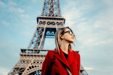 Wall Mural - Style redhead girl in red coat and bag at parisian street with view at Eiffel tower in autumn season time