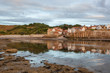 reflection of robin hoods bay on sea at low tide
