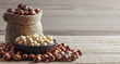 Hazelnuts, filbert in burlap sack and in bowl on brown vintage table. heap or stack of hazelnuts. Hazelnut background, healty food
