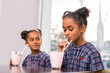© zinkevych - Fruit cocktail. Curly dark-haired schoolgirl sipping her milk and fruit cocktail sitting near her sister