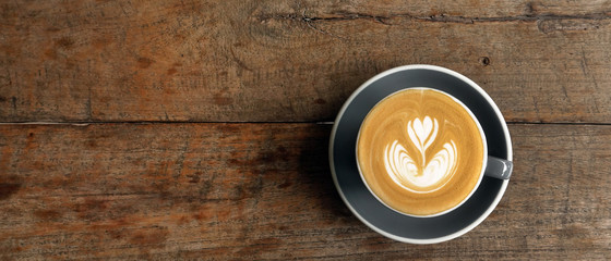 a cup of latte art coffee on wooden background