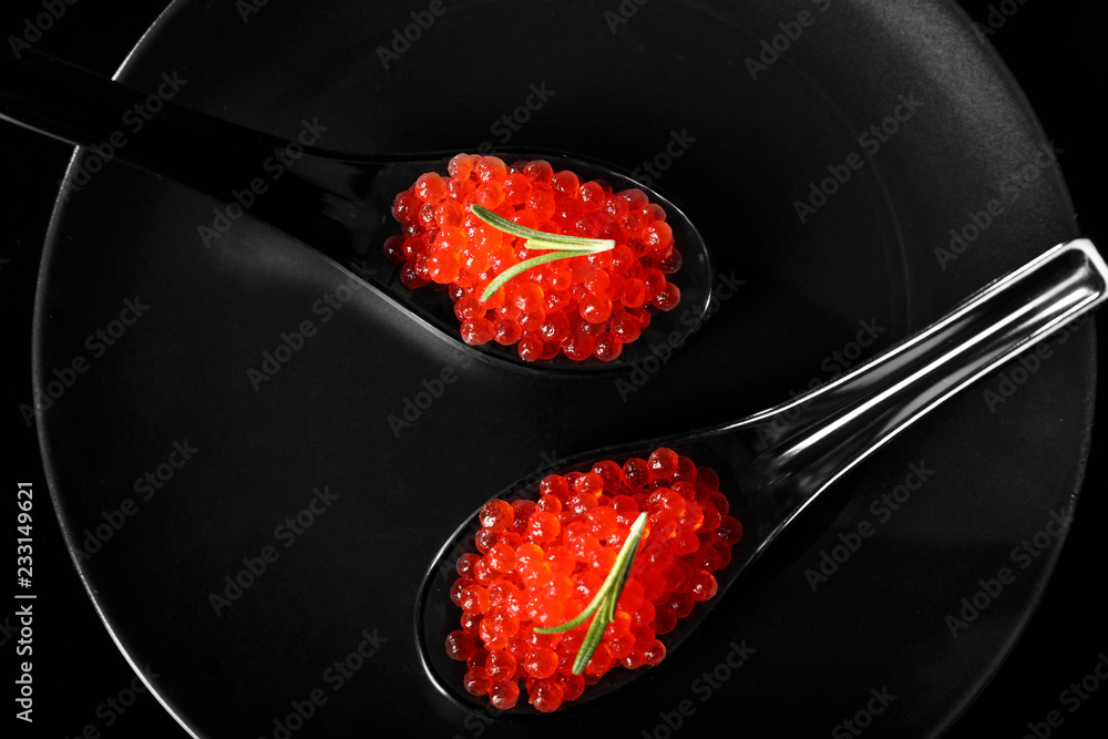 Spoons with red caviar on dark plate