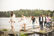 © Maskot - Multi-ethnic friends on jetty over lake during weekend getaway