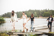 © Maskot - Multi-ethnic friends walking on jetty over lake during weekend getaway
