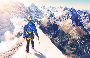 Fototapete - Climber reaches the summit of mountain peak. Climbing and mountaineering sport concept.