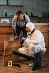 Wall Mural - forensic investigator showing picutes on camera to male detective at crime scene