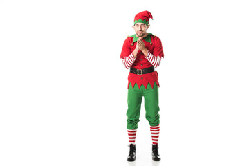 Wall Mural - excited man in christmas elf costume looking at camera and rubbing hands in anticipation isolated on white