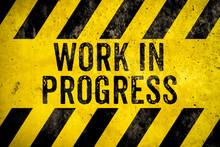 Work In Progress Warning Sign Text With Yellow And Black Stripes Painted Over Concrete Wall Cement Texture Background. Concept For Do Not Enter The Area, Caution, Danger, Construction Site.