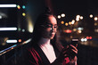 © LIGHTFIELD STUDIOS - attractive asian girl in burgundy kimono and glasses using smartphone on street with neon light in evening, city of future concept