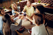 © chika_milan - Friends making a toast while sitting in restaurant. Multi-ethnic group.