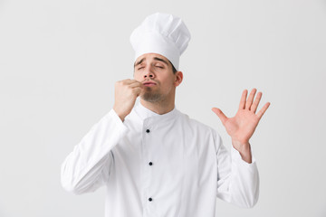 Wall Mural - Handsome young man chef indoors isolated over white wall background.