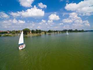 Wall Mural - Aerial view of yacht sailing on Niegocin Lake, Gizycko town in the background, Mazury, Poland