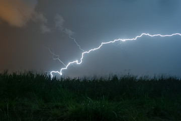Wall Mural - a powerful horizontal lightning bolt curves and strikes down to the earth