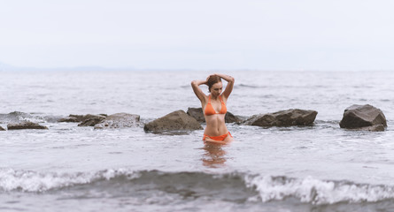 Wall Mural - Beautiful woman in a orange bikini in the sea.