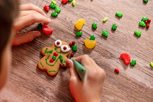Child Decorates Gingerbread Cookie. The Gingerbread Man On A Wooden Table. The Concept Of Preparation For Christmas