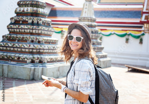 Stampa su Tela Young beautiful happy smiling european woman with smartphone in hands in a hat a