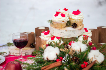 Festive table setting for Christmas for two with cupcakes, red wine