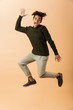 © Drobot Dean - Full length photo of amusing african american guy wearing sweater laughing and jumping, isolated over beige background