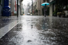 Rainy Day In A City With People Walking On Sidewalk And Holding Umbrellas In The Background (Bunkyo District, Tokyo, Japan)