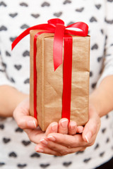 Wooman holding a gift box tied with red ribbon in the hands