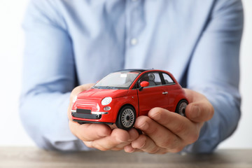 Male insurance agent holding toy car, closeup