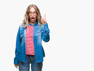 Wall Mural - Beautiful young blonde woman wearing glasses over isolated background pointing finger up with successful idea. Exited and happy. Number one.