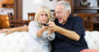 © Minerva Studio - Mature couple fighting for remote control on a sofa