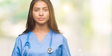 Sticker - Young arab doctor surgeon woman over isolated background with serious expression on face. Simple and natural looking at the camera.