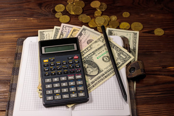 Notepad with dollars, pencil and calculator on wooden desk. Financial planning concept