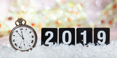 2019 New Years eve celebration. Minutes to midnight on an old watch, bokeh festive background