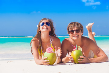 Wall Mural - couple lying on a tropical beach in Barbados and drinking a coconut cocktail