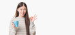 © Krakenimages.com - Young Chinese woman over isolated background driking cup of coffee doing ok sign with fingers, excellent symbol