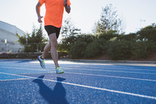 Athlete Running On A Running Track Alone. Runner Sprinting On A Blue Rubberized Running Track.