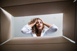 © F8  \ Suport Ukraine - Delivery, relocation and unpacking concept. Surprised young female opening a carton box and looking peering inside with widely opened eyes