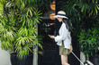 © LUMINA IMAGES - Pretty Asian woman vacationer walking with suitcase and looking at her cell phone.