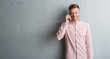 © Krakenimages.com - Young redhead man over grey grunge wall talking on the phone with a happy face standing and smiling with a confident smile showing teeth