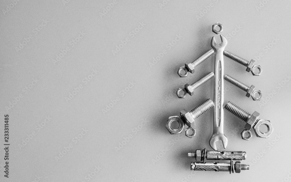 Wrench, nuts and bolts decorated as Christmas tree on a gray background ...