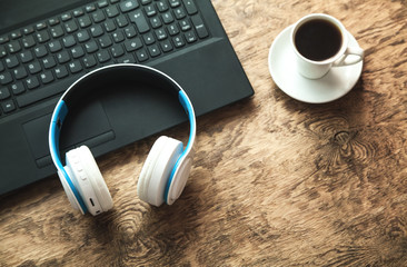 Headphones with laptop and coffee on wooden background.